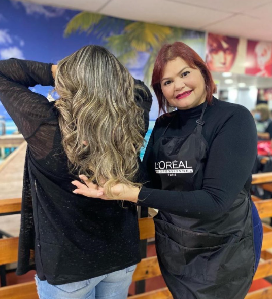 Estilista de Chiqui Paz Studio mostrando el resultado de color y ondas en el cabello de una clienta